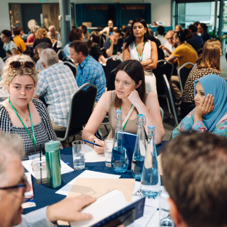 people sit around a table listening to each other speak