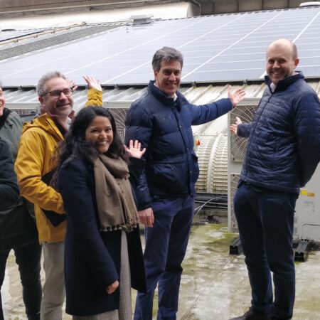 Ed Miliband poses with a group in front of a rooftop solar installation