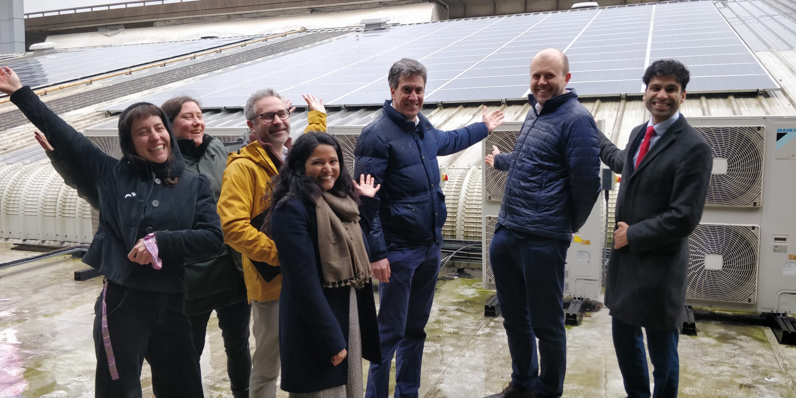 Ed Miliband poses with a group in front of a rooftop solar installation