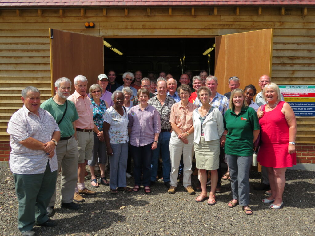 A group of people stand in front of two open double doors in a wooden cladded building