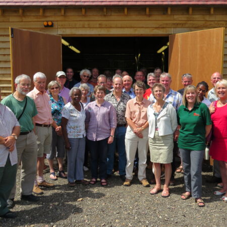 A group of people stand in front of two open double doors in a wooden cladded building