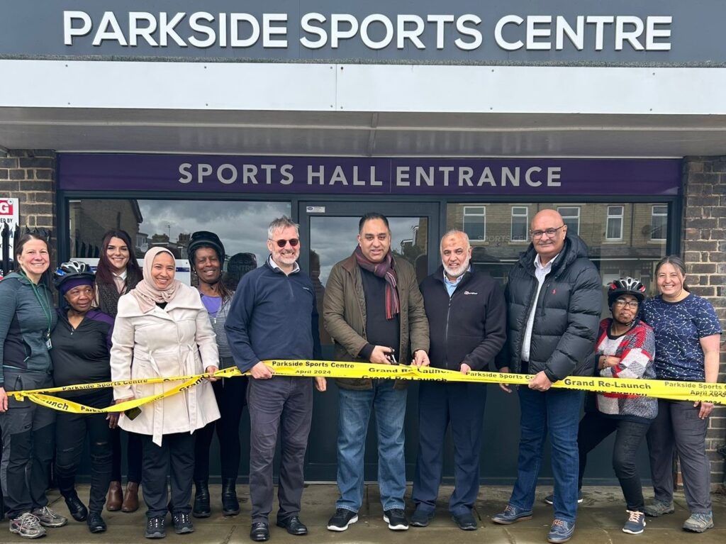 a group of people stand behind a ribbon at the entrance of the Parkside Sports Centre