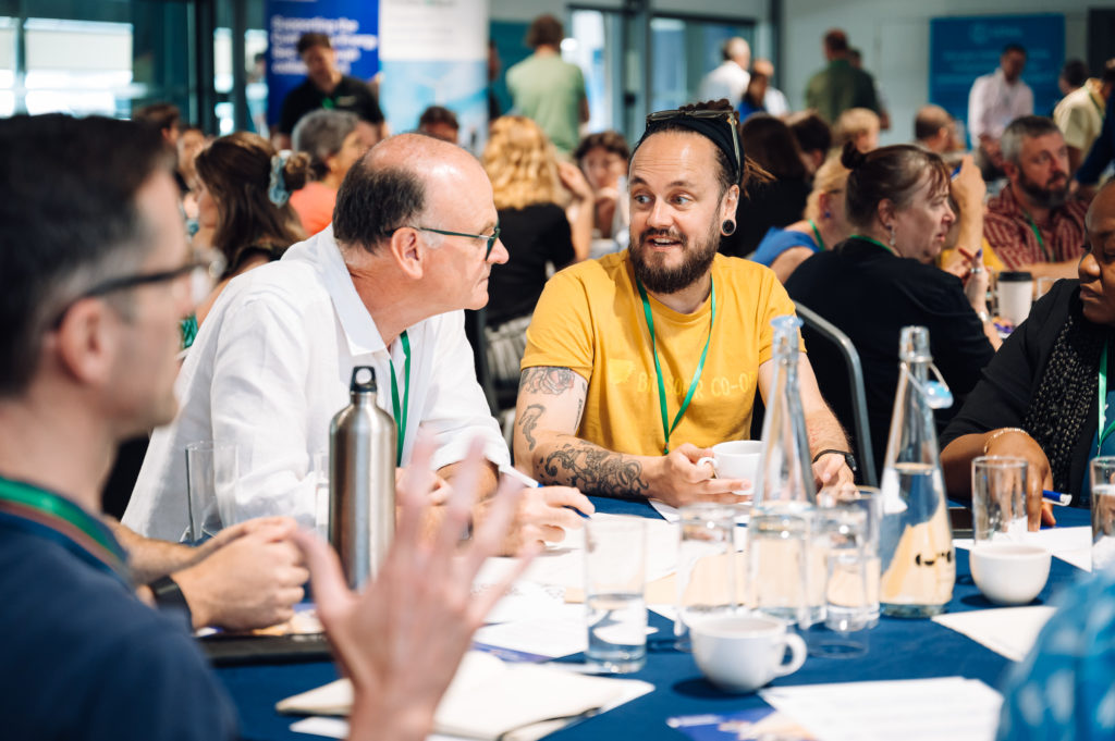two people sat at a round table during a conference have a conversation