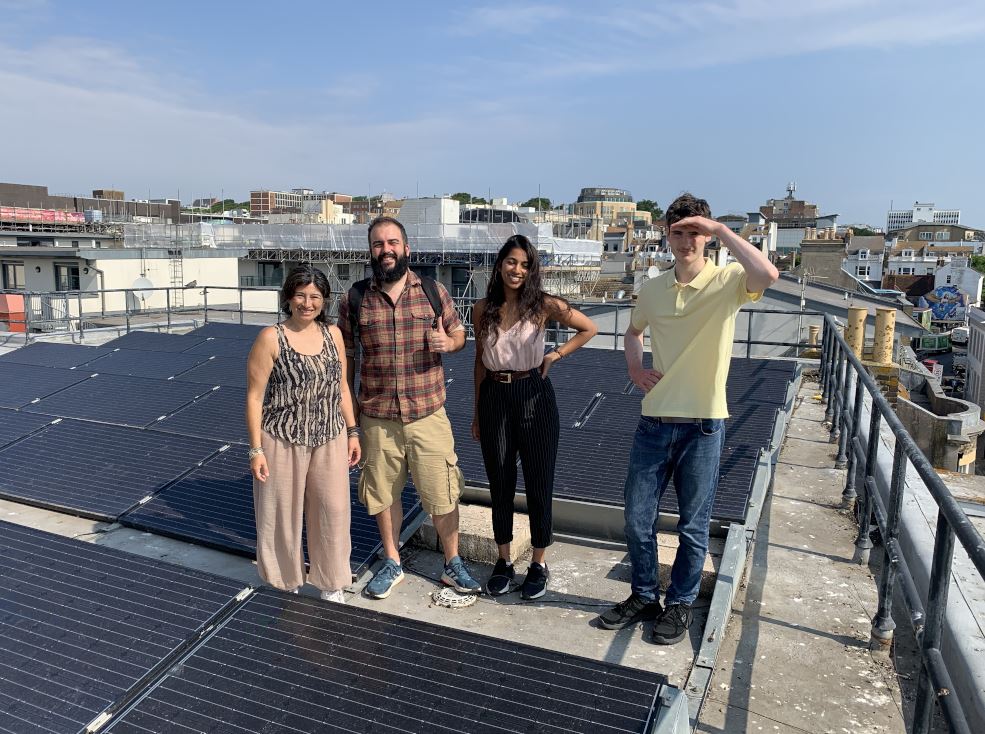 a group of people stand on a roof next to solar panels