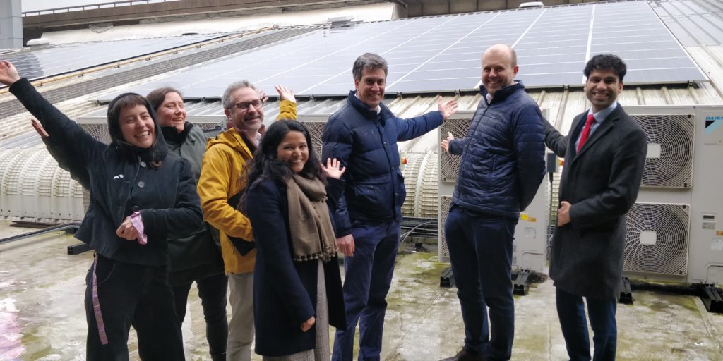 a group of people stand in front of solar panels