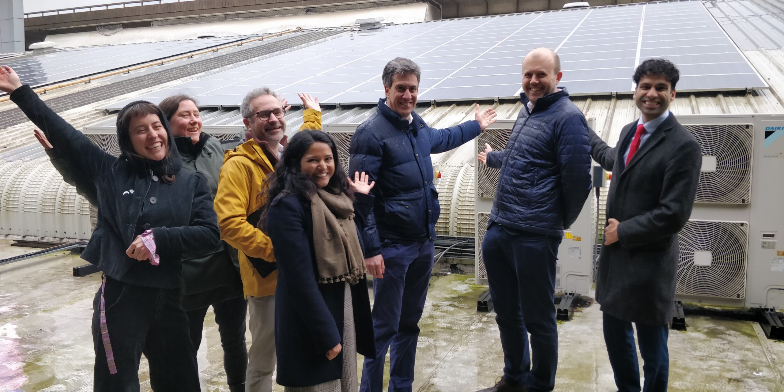 Ed Miliband poses with a group of community energy practitioners in front of a solar installation