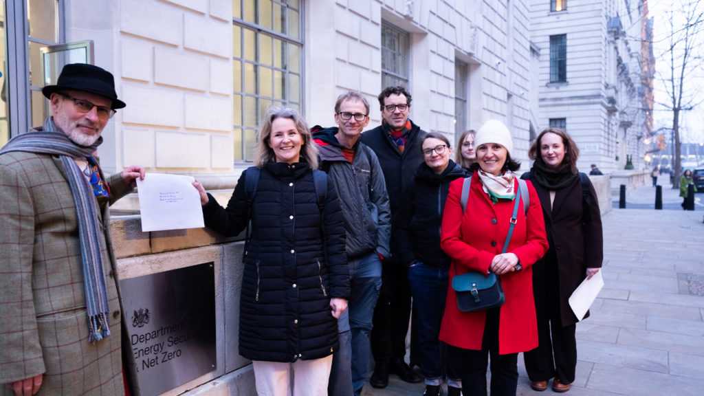 A group of people stand with a letter in front of the Department for Energy Security and Net Zero